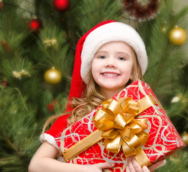 Schattig lachende klein meisje in kerstmuts met een doos van de gift Rechtenvrije Stockafbeeldingen