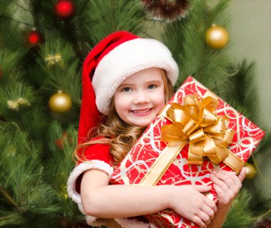 Santa şapka hediye kutusu ile sevimli gülümseyen küçük kız