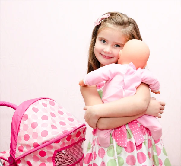 Мила усміхнена маленька дівчинка грає зі своїм іграшковим екіпажем і лялькою Ліцензійні Стокові Фото