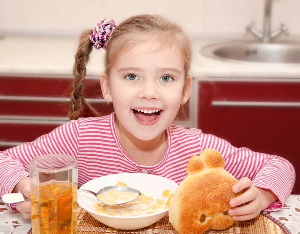 Cute smiling little girl having breakfast cereals with milk — Stock Photo, Image