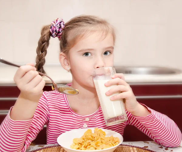 Sød lille pige, der har morgenmad drikker mælk - Stock-foto