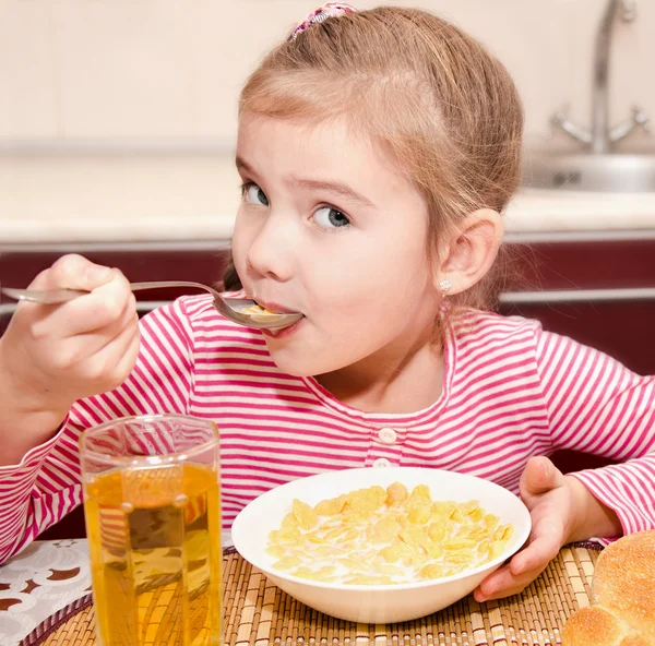 Cute little girl having breakfast cereals with milk and juice — Stock Photo, Image