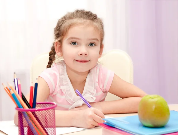 Linda niña está escribiendo en el escritorio — Foto de Stock