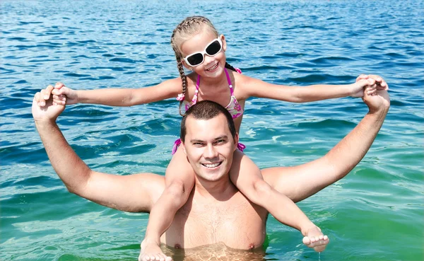 Smiling little girl sitting on father's shoulders — Stock Photo, Image