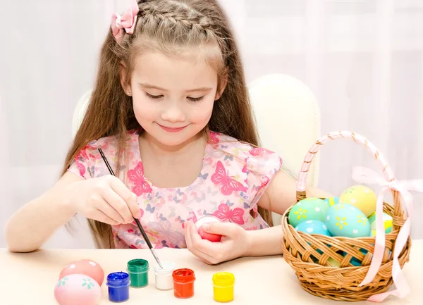 Милая маленькая девочка рисует красочные пасхальные яйца — стоковое фото