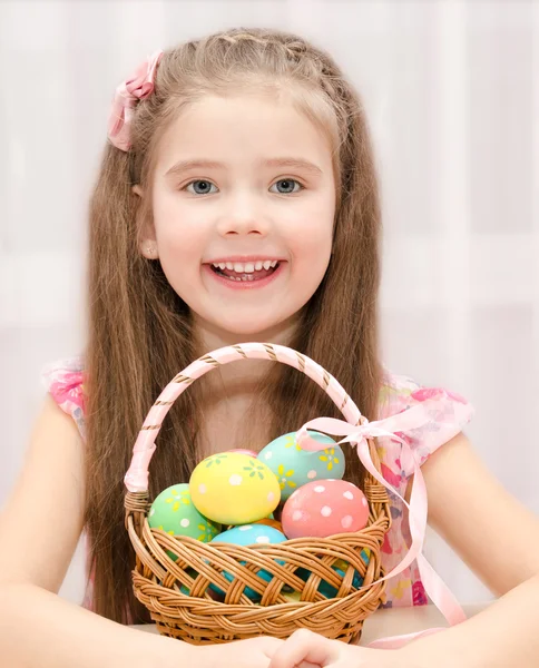 Schattig klein meisje met mand vol kleurrijke paaseieren — Stockfoto