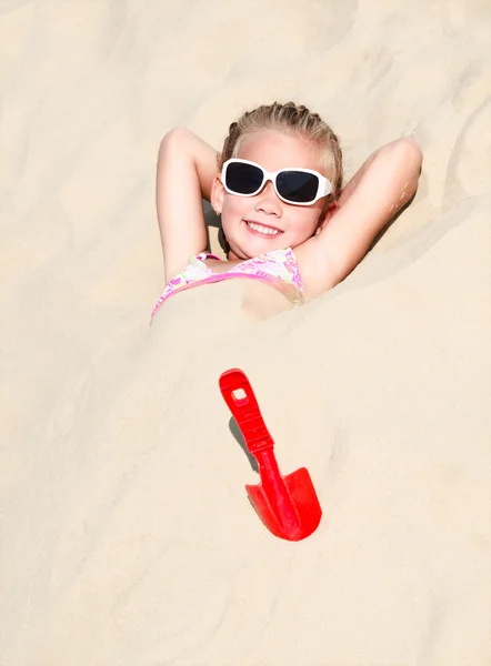 Glad söt liten flicka liggande i sanden — Stockfoto