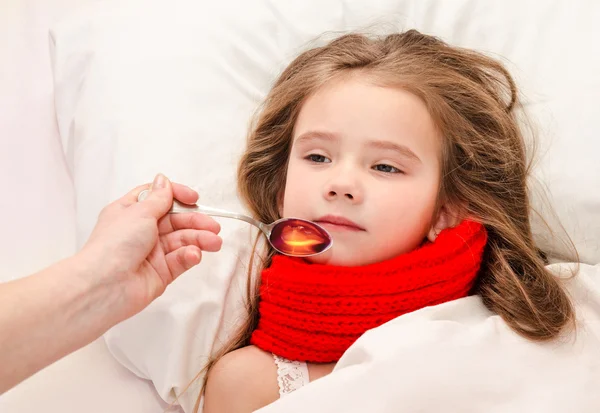 Chory dziewczynka w łóżku biorąc lek — Zdjęcie stockowe