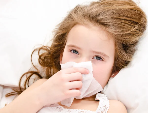 Niña acostada en la cama y sonándose la nariz — Foto de Stock