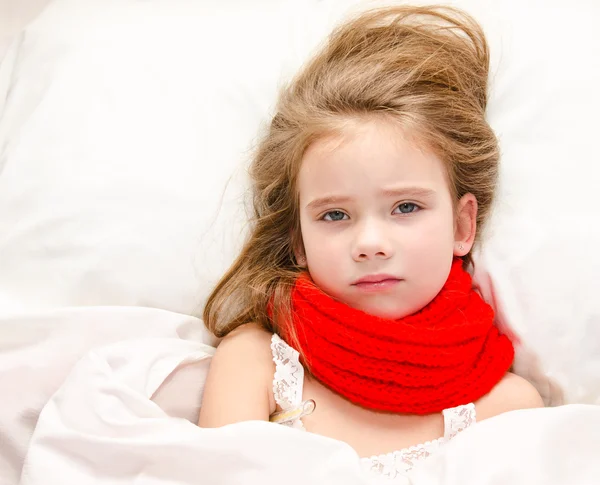 Malá holka ležící v posteli s teploměrem — Stock fotografie