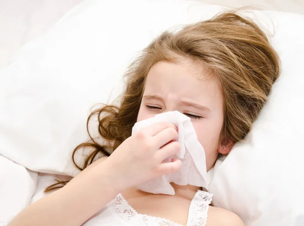 Meisje liggend in het bed en blazen haar neus — Stockfoto