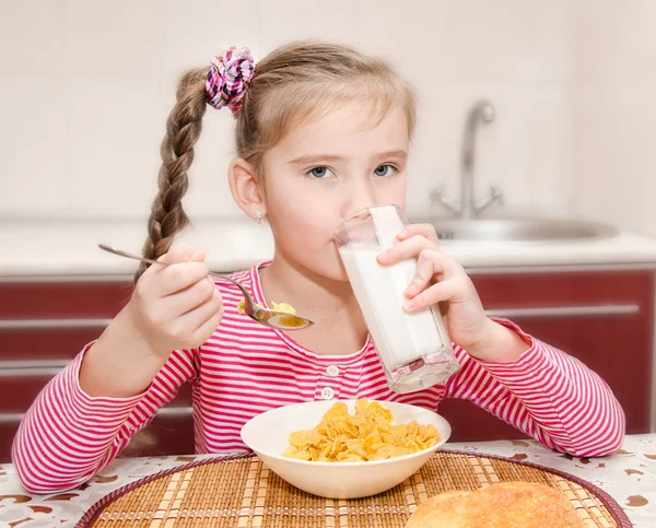 Sød lille pige, der har morgenmad drikker mælk - Stock-foto