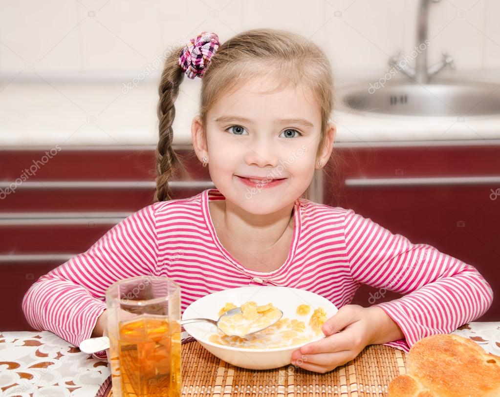 Cute smiling little girl having breakfast cereals with milk 