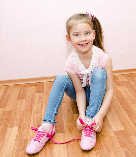 Cute smiling little girl tying her shoes — Stock Photo, Image