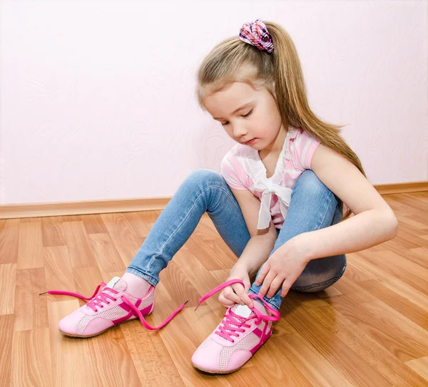 Cute smiling little girl tying her shoes — Stock Photo, Image