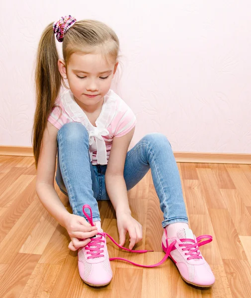 Cute smiling little girl tying her shoes Royalty Free Stock Photos