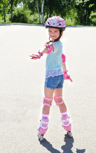 Jolie petite fille souriante en patins à roulettes roses — Photo