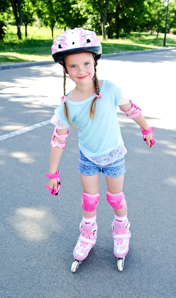 Jolie petite fille souriante en patins à roulettes roses — Photo