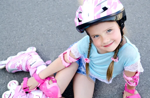 Schattig lachende klein meisje in roze rolschaatsen en beschermende ge — Stockfoto