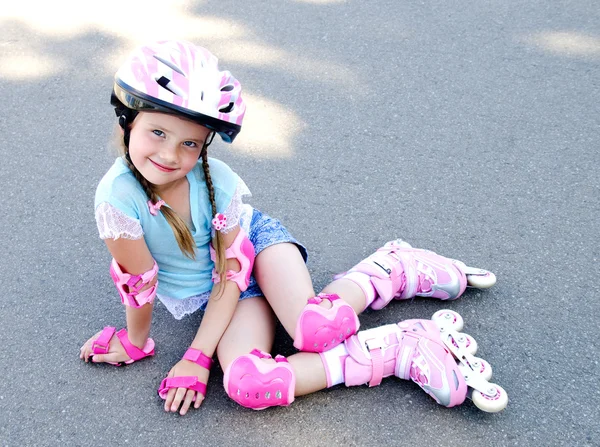 Roztomilý usměvavá holčička v růžových kolečkové brusle — Stock fotografie