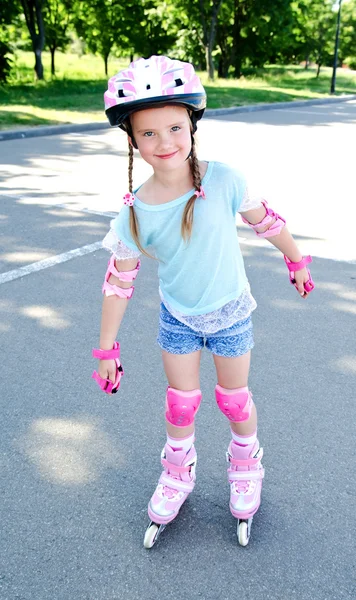 Cute smiling little girl in pink roller skates Stock Picture