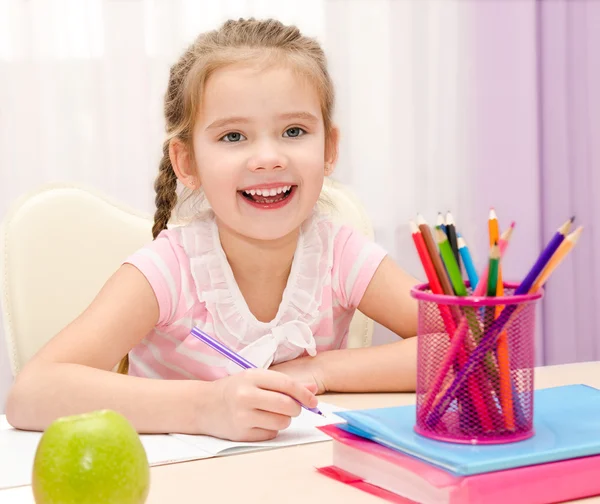 Söt liten flicka skriver vid skrivbordet — Stockfoto