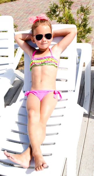 Little girl lying on a chaise lounge and sunbathing — Stock Photo, Image