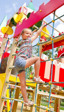 oyun alanı ekipmanı üzerinde oynarken küçük kız gülümseyerek 