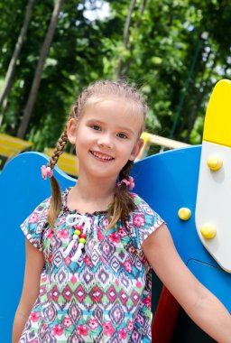 oyun alanı ekipmanı üzerinde oynarken küçük kız gülümseyerek 