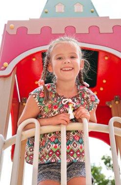 oyun alanı ekipmanı üzerinde oynarken küçük kız gülümseyerek 