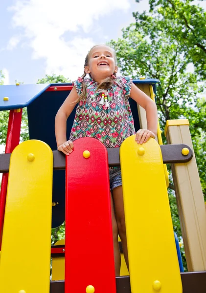 Smiling little girl playing on playground equipment — Stock Photo, Image