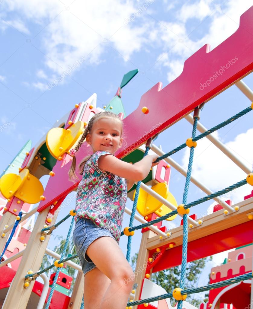 Smiling little girl playing on playground equipment Stock Photo by