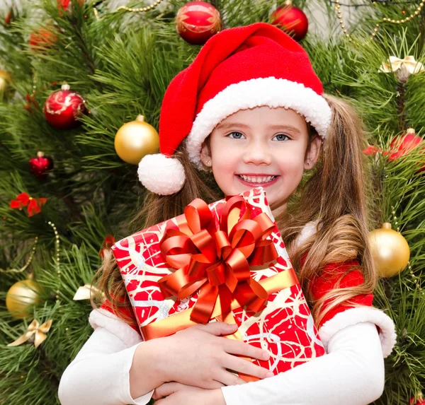 Hediye kutusu ile Noel Baba şapkası, sevimli küçük kız — Stok fotoğraf