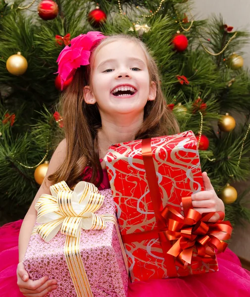 Petite fille avec des boîtes cadeaux près de l'arbre de Noël — Photo