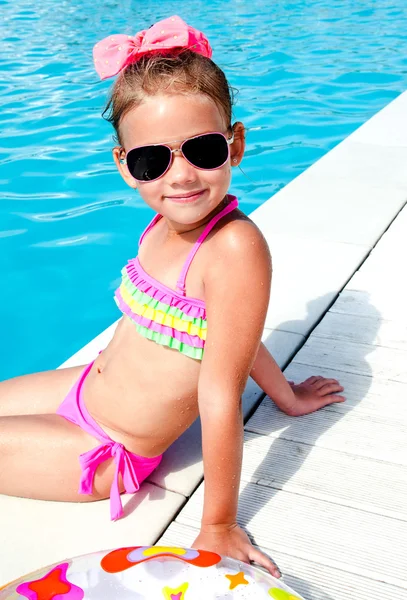 Söt liten flicka sitter nära pool — Stockfoto