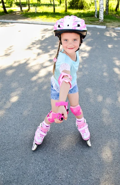 Cute smiling little girl in pink roller skates Stock Photo