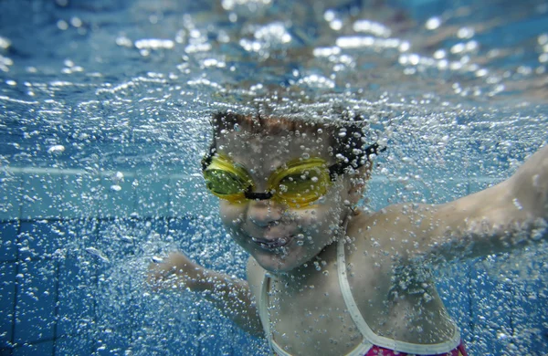 Divertente felice bambino ragazza nuotare sott'acqua in una piscina con un sacco di bolle d'aria — Foto Stock