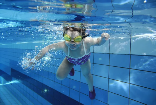 Divertente felice bambino ragazza nuotare sott'acqua in una piscina con un sacco di bolle d'aria — Foto Stock