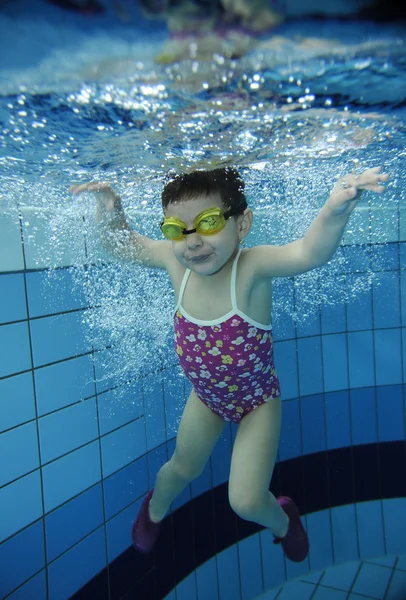 Lustige fröhliche Kleinkind Mädchen schwimmen unter Wasser in einem Pool mit vielen Luftblasen — Stockfoto