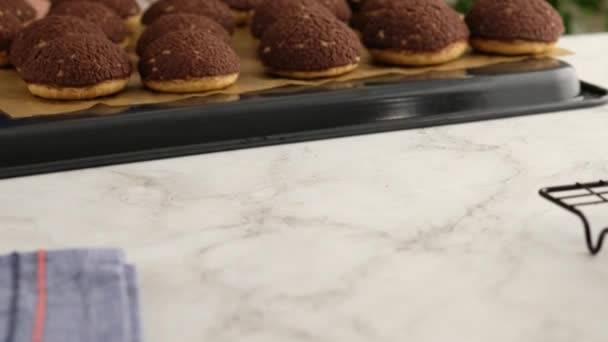 Matlagning choux eller profiteroles, tar kvinnliga händer ut färdiga choux från ugnen, närbild. Matlagning krämig och bär choux med choklad krabba. Vaniljchoux med chokladkrabba. — Stockvideo