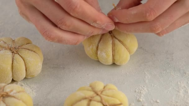 Μαγειρεύω κουλουράκια κολοκύθας. Τα γυναικεία χέρια σχηματίζουν ένα κουλούρι κολοκύθας από ζύμη και κλωστή, από κοντά. Φθινοπωρινή ιδέα Πρωινά ψωμάκια. Νωπά ψωμάκια. — Αρχείο Βίντεο