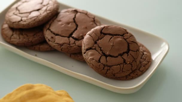 Bolachas de chocolate recém-feitas. As mãos femininas põem biscoitos de chocolate em uma chapa em uma mesa de vidro. Fechar.. — Vídeo de Stock