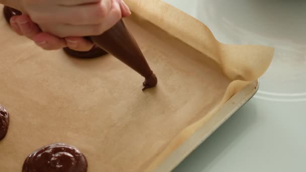 Frisch gebackene Schokoladenkekse. Weibliche Hände legen Teig aus einer Teigtasche für Plätzchen mit Schokoladenchips auf ein Backblech. Nahaufnahme. — Stockvideo