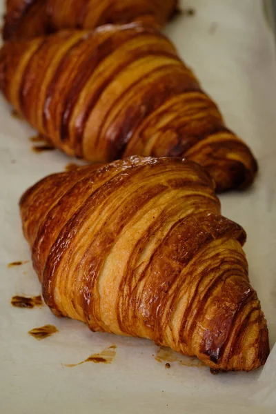 Imagem de perto de croissants deliciosos franceses nas prateleiras na padaria. Fabricação de processos — Fotografia de Stock