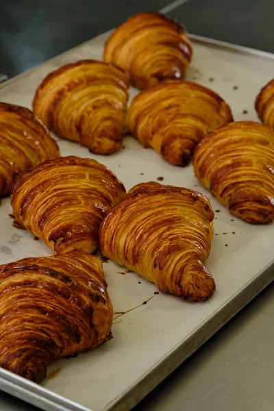 Imagem de perto de croissants deliciosos franceses nas prateleiras na padaria. Fabricação de processos — Fotografia de Stock