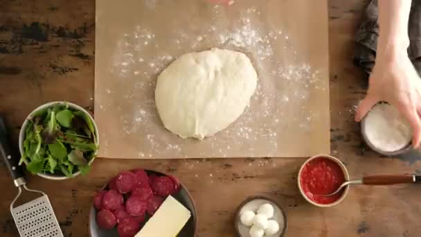 Vue de dessus, mains féminines mettre la pâte, préparer la pizza italienne avec sauce, tomates, assaisonnements, saucisses pepperoni, épinards, légumes verts, fromage mozzarella. De la pâte à pain. Pizza pepperoni . — Video