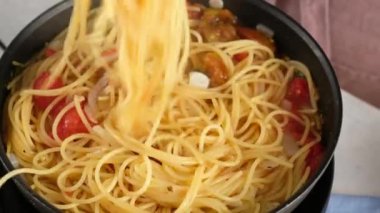 Bir tava pastası. Kadın bir aşçının yakın plan resmi. Bir tava makarna pişiriyor ve içine karıştırıyor..