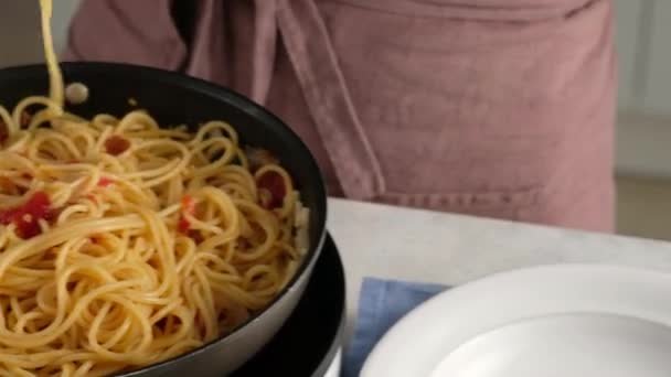 JEDNA PAN PASTA. Detailní záběr kuchařky položí talíř těstovin z pánve na talíř. Těstoviny na vaření. — Stock video