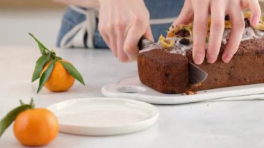 Bir kadın masada roma batırılmış bir kek kesiyor. Arka planda fenerler olan bir Noel atmosferi. Ev yapımı Noel çöreği. Kurutulmuş meyveli kek. Geleneksel kek Noel için..