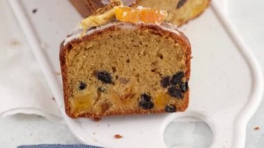 Üst Manzara. Masada roma batırılmış dilimlenmiş meyveli kek var. Arka planda fenerler olan bir Noel atmosferi. Ev yapımı Noel çöreği. Kurutulmuş meyveli geleneksel kek. Kamera hareketi.